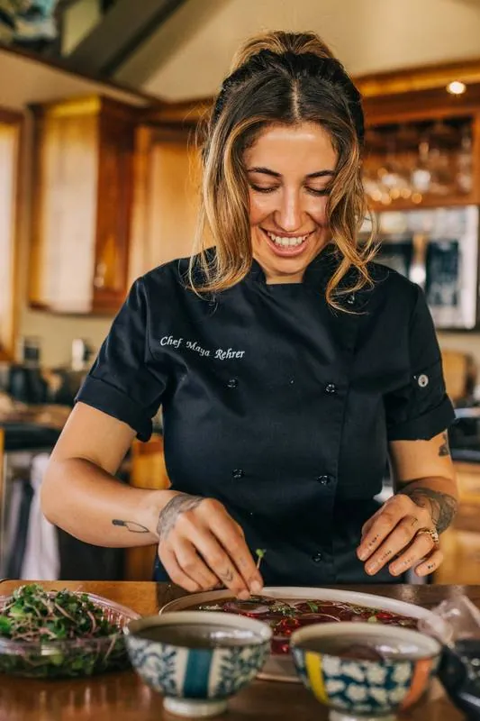 Chef Maya Rehrer smiling while plating a dish