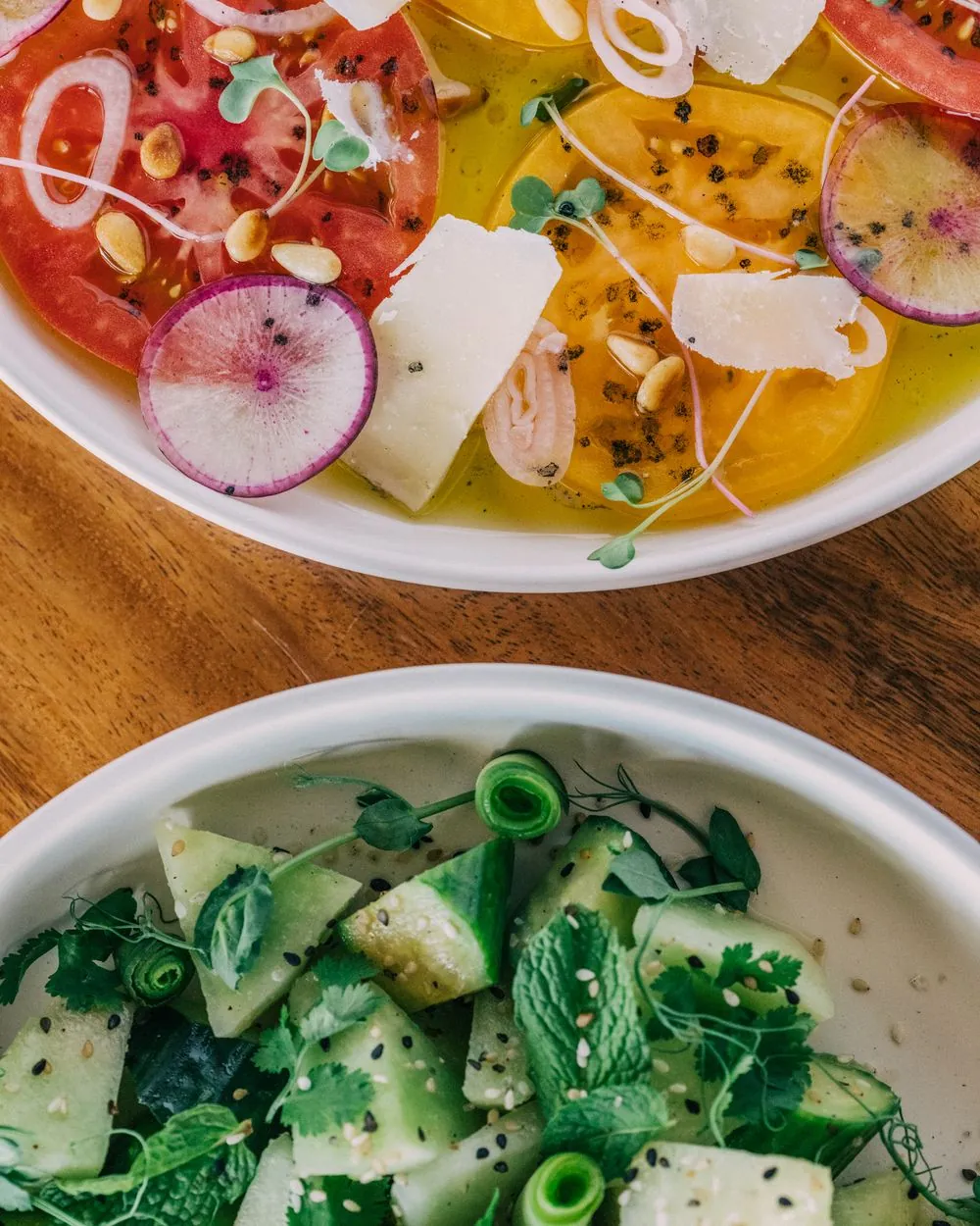 Heirloom tomato carpaccio beside a cucumber herb salad